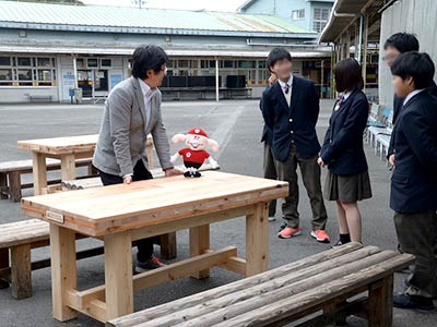 寄贈された木製のテーブルと談笑する高校生